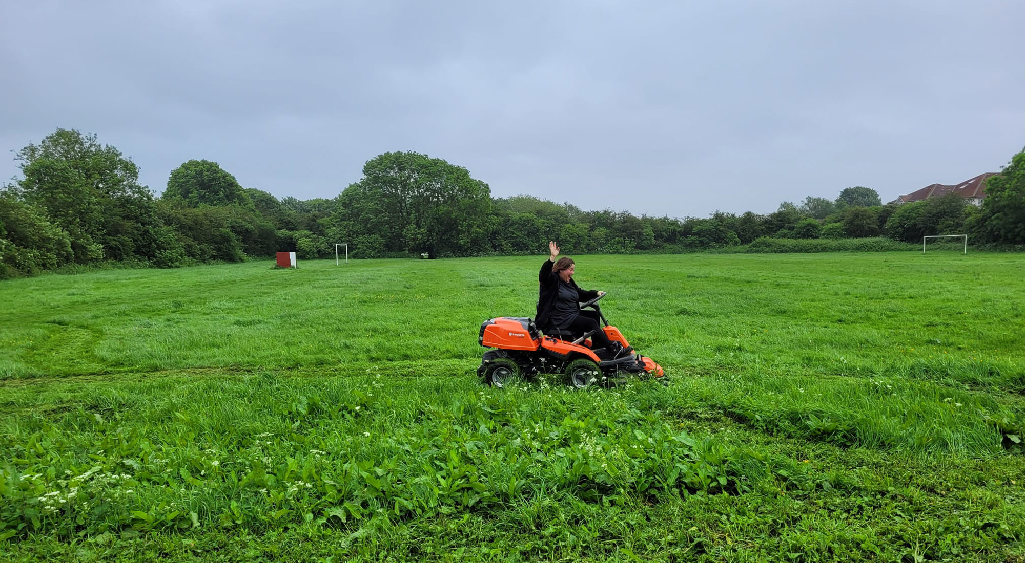 Ruben's Voice volunteer using a ride-on lawnmower