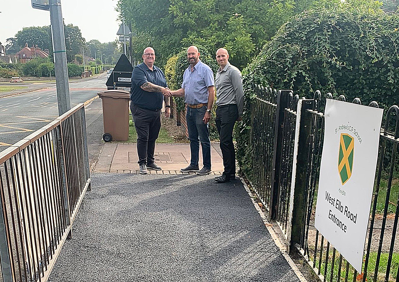 L_R James Stevenson, Senior Project Manager at GRAHAM shakes hands with Cllr Gary McMaster, on the new path at St Andrews Primary School, Kirk Ella with Dan Cawthra, Head of Stakeholder & Community Engagement at GRAHAM looking on.